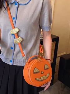 Close-up of a vibrant orange Halloween pumpkin crossbody bag with glitter details.