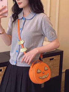 Detailed view of an orange pumpkin crossbody bag with gold glitter bat charms