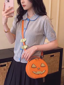 Detail shot of a creative orange pumpkin shaped crossbody bag with glitter jack-o-lantern face