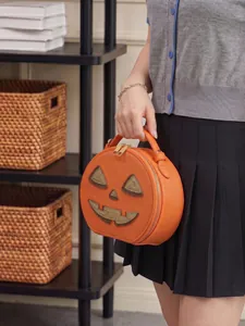 Detailed shot of a pumpkin-shaped Halloween handbag held by a model in a cozy room set