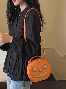 Detail view of creative pumpkin-shaped shoulder bag for Halloween with gold glitter face