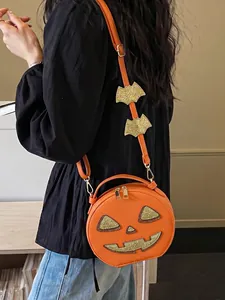 Detail of a festive orange pumpkin crossbody bag with glittery bat charms on the strap.