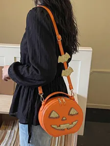 Detailed view of the orange Halloween pumpkin crossbody bag with bat strap decorations.