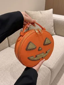 Detailed view of an orange Halloween pumpkin crossbody bag featuring a glittery face design