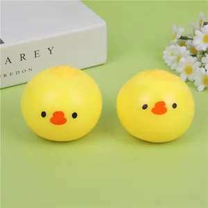Close-up of cute yellow round chick squeeze toys on a green surface with white flowers.