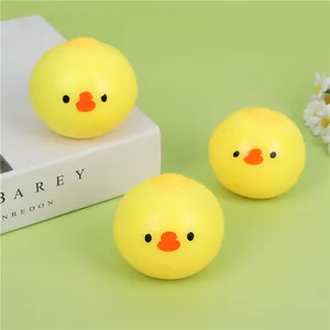 Close-up of three cute yellow round chick squishy stress relief toys on a green surface