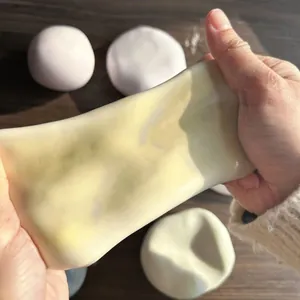 Gros plan de mains étirant un jouet mochi squishy jaune pour soulager le stress
