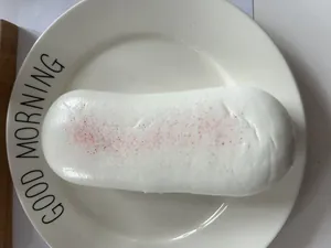 Detailed view of realistic PU simulation bread squishy toy on a white plate.