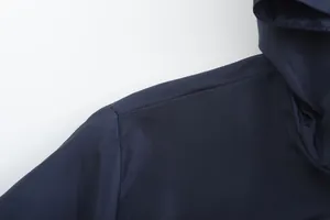 Detailed macro view of the shoulder seam and durable fabric on a navy blue men's hooded jacket