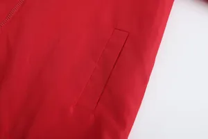 Close-up of side pocket and zipper detail on a red lightweight men's sports jacket