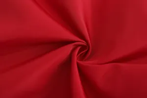 Macro detail of breathable red sport fabric showing twill texture and smooth finish