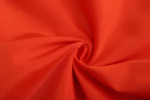 Close-up macro view of vibrant red breathable fabric texture for men's sports jacket