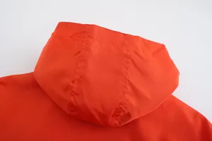 Close-up detail of the breathable hood on a lightweight orange men's jacket