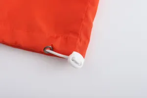 Close-up of orange breathable jacket hem featuring white drawstring and plastic toggle