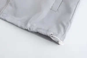 Close-up of men's lightweight grey jacket hem showing adjustable drawstring and toggle.