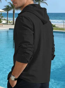 Detailed view of men's black hooded linen shirt at a sunny poolside resort setting