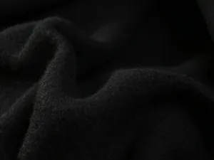 Macro close-up showing soft black fleece fabric texture of casual wide-leg trousers