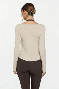 Back view of a beige long-sleeved yoga top featuring a stylish dark neck strap detail.
