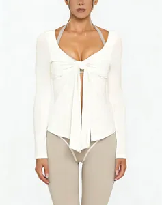Close-up detail of a white V-neck yoga top featuring a front tie knot and long sleeves