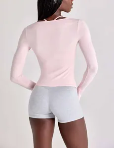 Rear view of pink long-sleeve yoga top with strap detail and grey fitness shorts