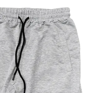 Close-up of grey joggers waistband with black drawstring and side pocket detail
