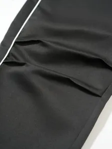 Makro-Detail der schwarzen Techwear-Hose mit plissiertem Knie und weißer Paspelierung