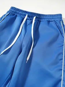 Detailansicht einer blauen Herren-Sporthose mit weißen Kordelzügen und weißen Seitenstreifen