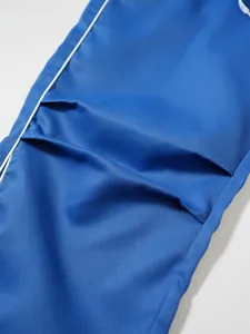 Detailaufnahme der Stofftextur und der blauen Falttasche dieser funktionellen Techwear-Hose