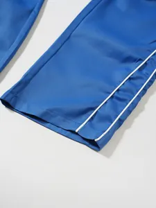 Detailansicht des blauen Saums einer Funktionshose mit weißen Paspeln und Gewebestruktur