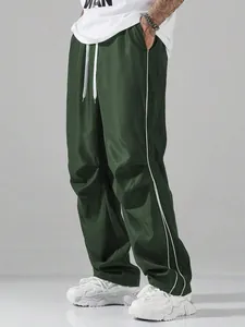 Detail shot of green wide-leg track pants with white side stripes and drawstring waist