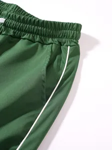 Detailansicht der grünen Sporthose für Herren mit elastischem Bund und Seitenstreifen