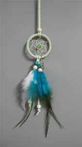 Detalle de un atrapasueños hecho a mano con plumas azules y verdes y pequeñas cuentas.
