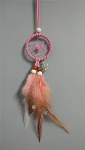 Detalle de un atrapasueños rosa con plumas y un colgante de pentagrama plateado.
