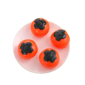 Lot de quatre jouets de décompression en forme de kaki orange sur une assiette rose pâle