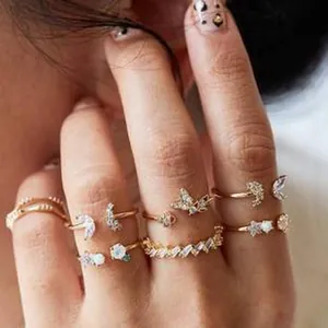 Detailed view of bohemian gold rings set with butterfly and moon motifs on fingers