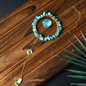 Handmade turquoise and iridescent crystal suncatcher pendant hanging on wood background
