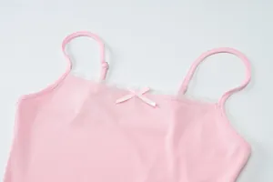 Detailopname van een roze geribbeld hemdje met kanten rand en een klein strikje