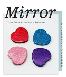 Primer plano de cuatro espejos de maquillaje plegables en forma de corazón con purpurina de colores.