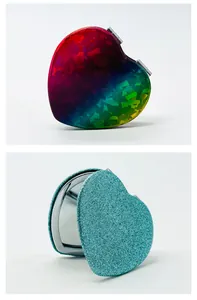 Primer plano de espejos compactos en forma de corazón con acabados arcoíris y brillo.