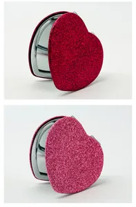 Primer plano de espejo compacto de purpurina con forma de corazón en rojo y rosa