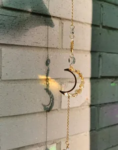 Détail d'un attrape-soleil en forme de croissant avec cristaux jaunes et prisme lumineux