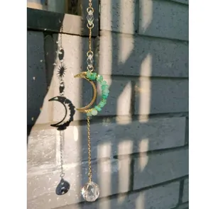 Gros plan d'un attrape-soleil en cristal avec lune, pierres vertes et boule de cristal