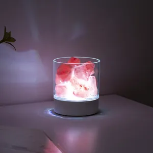 Close-up of a glowing Himalayan salt rock lamp in a transparent cylinder base.