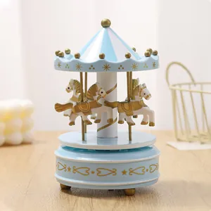 Detailed view of a blue and white carousel music box featuring golden horses on a wooden table.