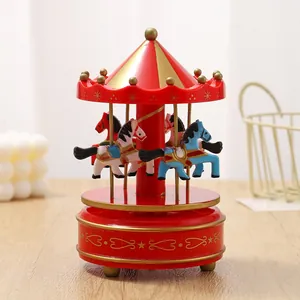Detailed view of a classic red and gold carousel music box on a wooden table