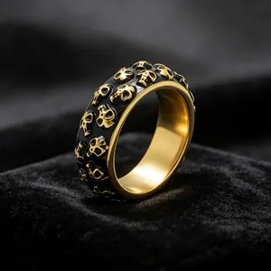 Gedetailleerde macro-opname van een herenring van titaniumstaal met gouden schedels.