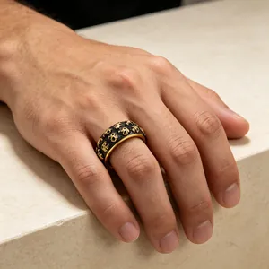 Detailopname van een heren punk ring van roestvrij staal met gouden doodshoofden in reliëf.