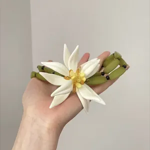 Vista detallada de un collar de flores de resina blanca con cuentas de bambú verde