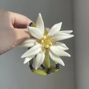 Primer plano de un gran accesorio de flor de resina blanca con elementos artísticos de bambú.
