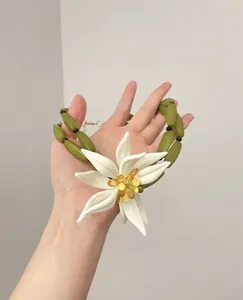 Vista detallada de un collar de flores de resina blanca con cuentas de bambú olivo.